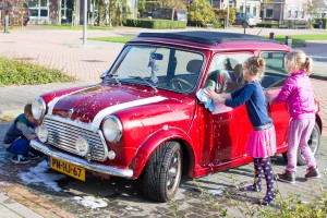 Kinderen poetsen retro Mini Cooper Cabrio huurauto